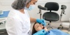 стоматолог проводит диагностику пациента перед лечением зубов под микроскопом