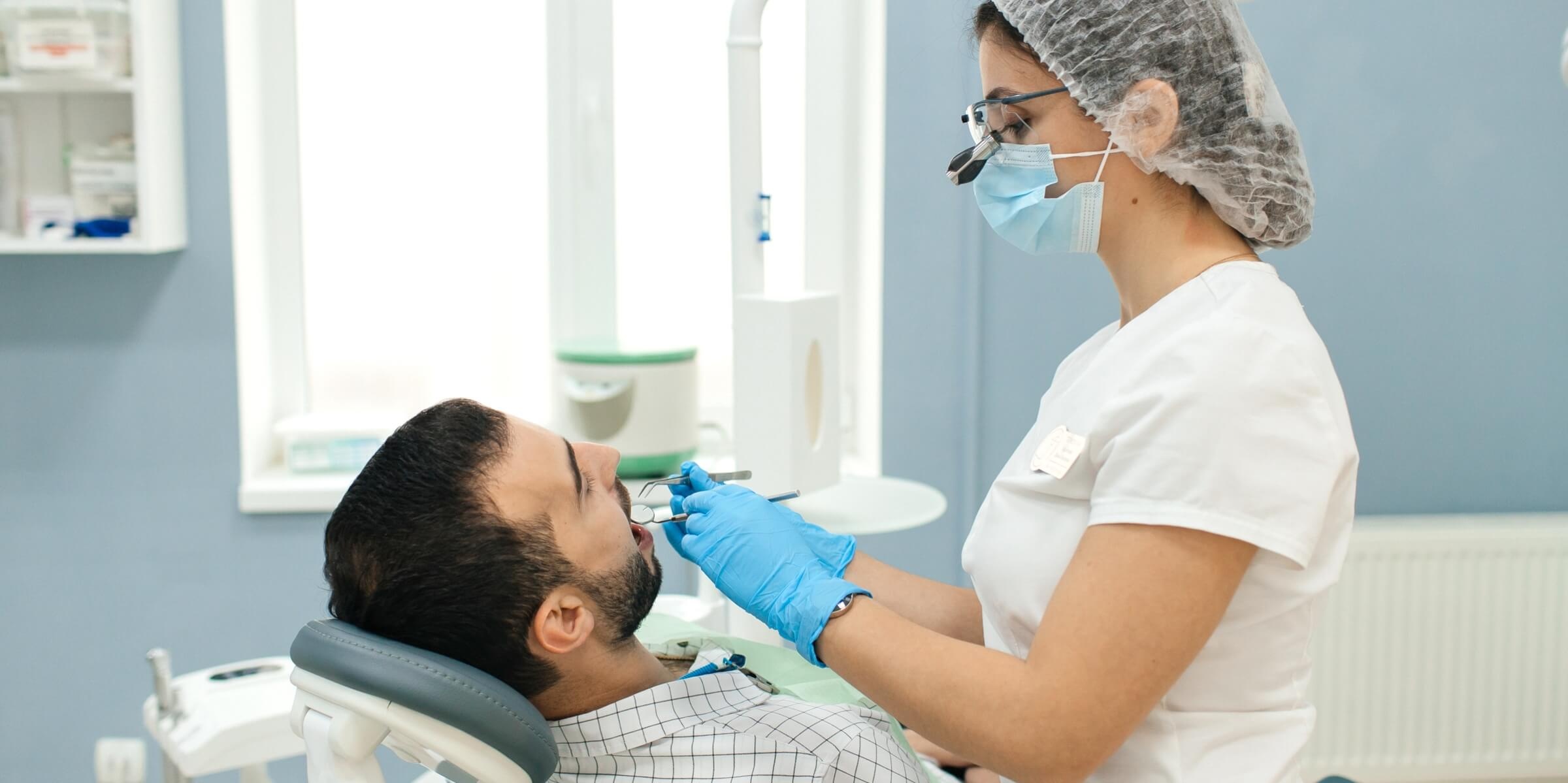 Стоматолог хирург заканчивает трансплантацию зуба