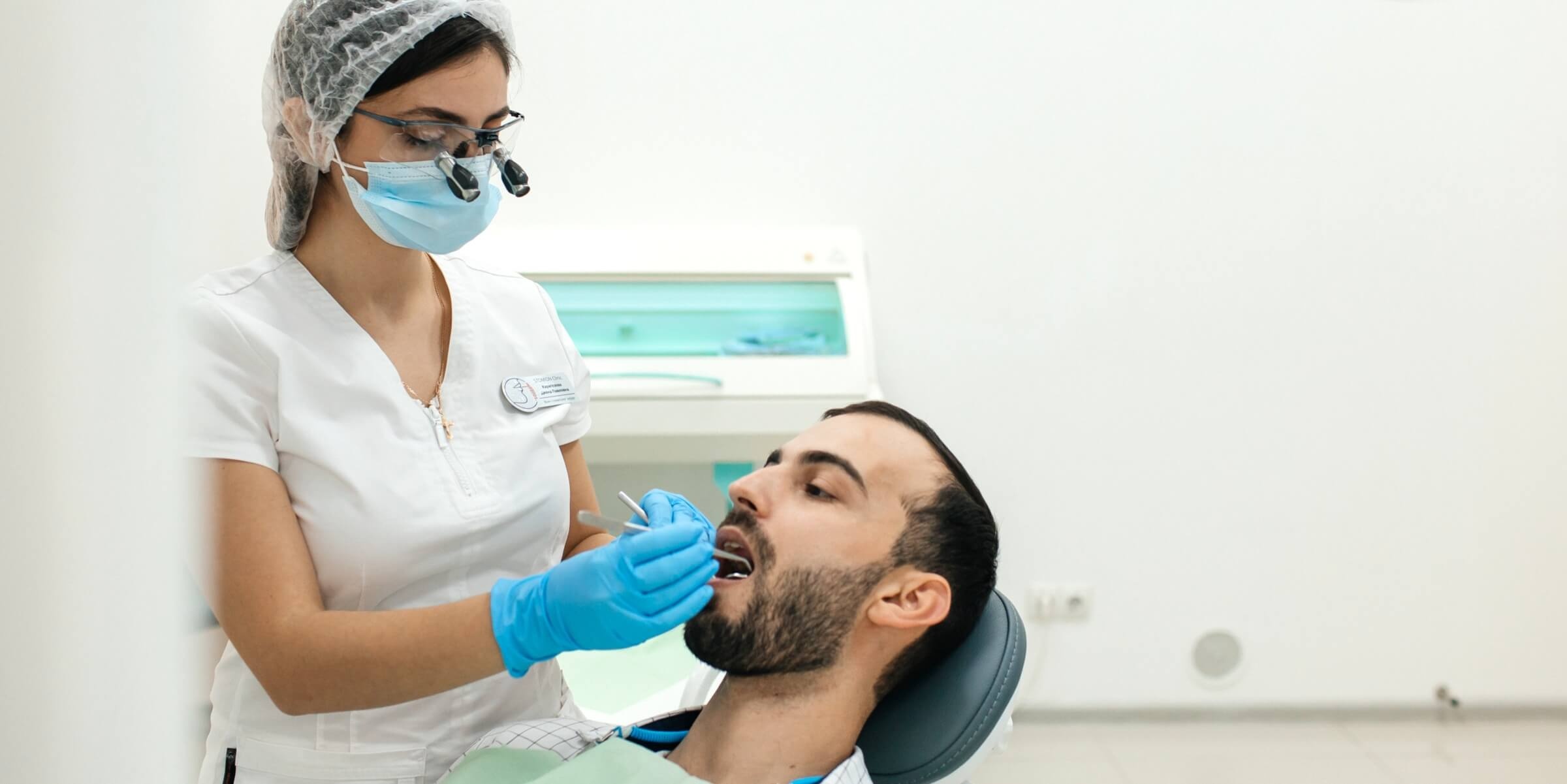 Хирург стоматолог проводит операцию по атравматичному удалению зубов
